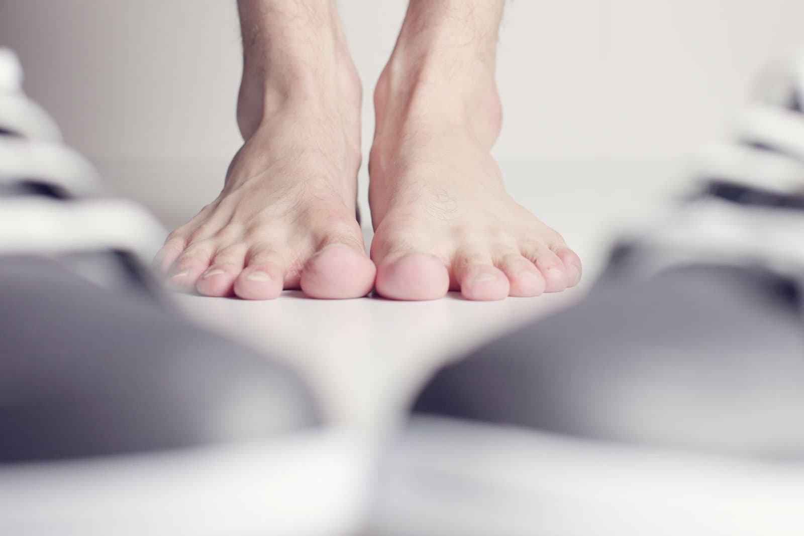 A man's bare feet standing between two shoes