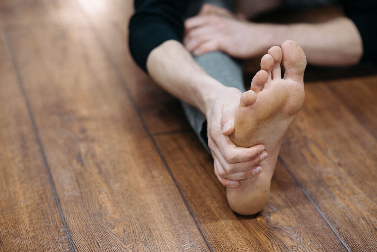 A man's bare sole, his hand at the ball of the foot