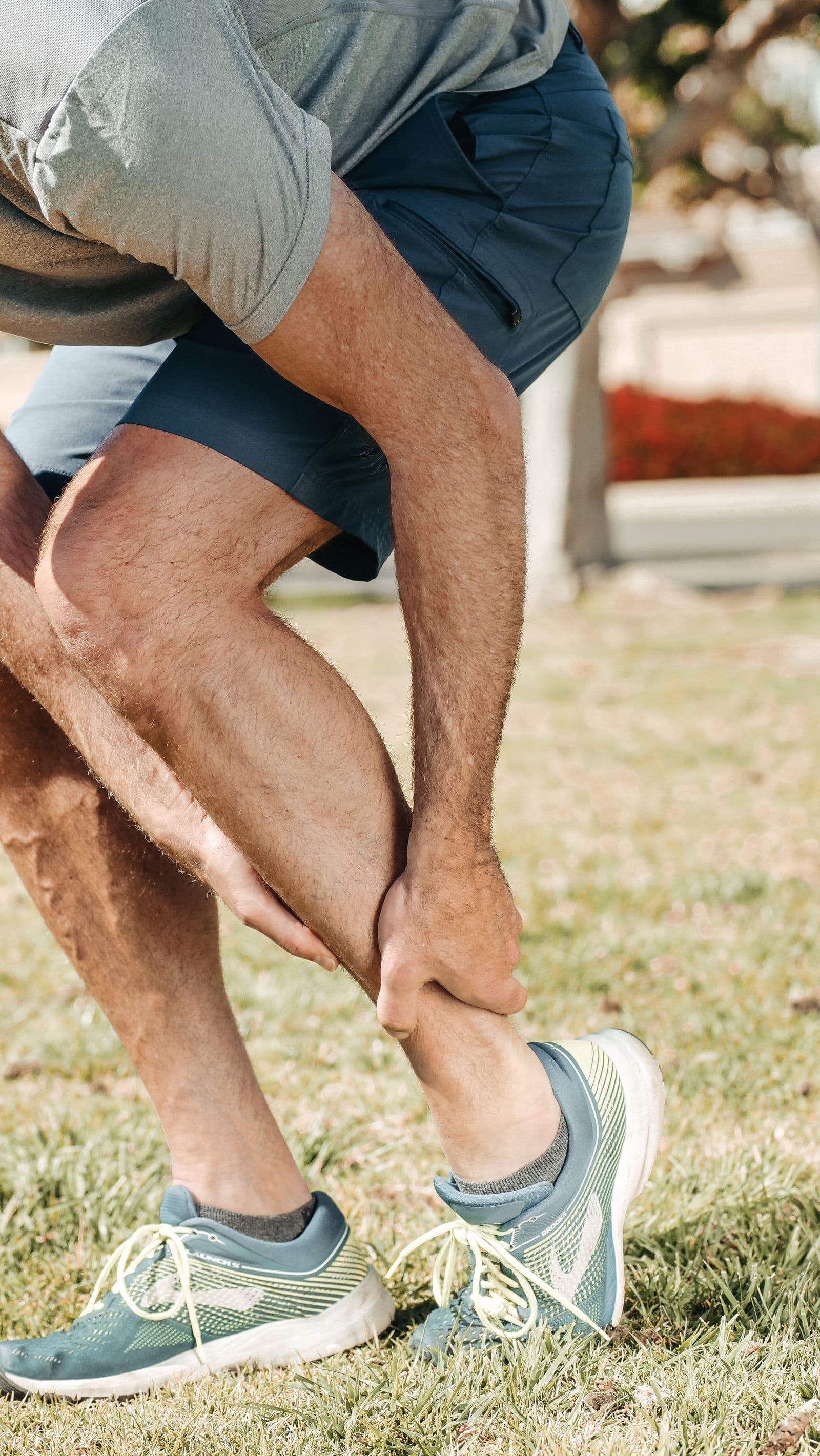 A man bent forward, holding his lower calf and ankle with both hands