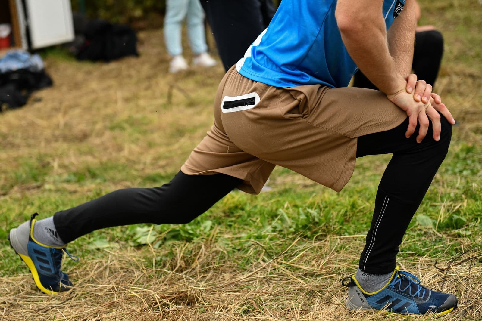 A man holding a lunge on grass, front knee bent, rear leg long