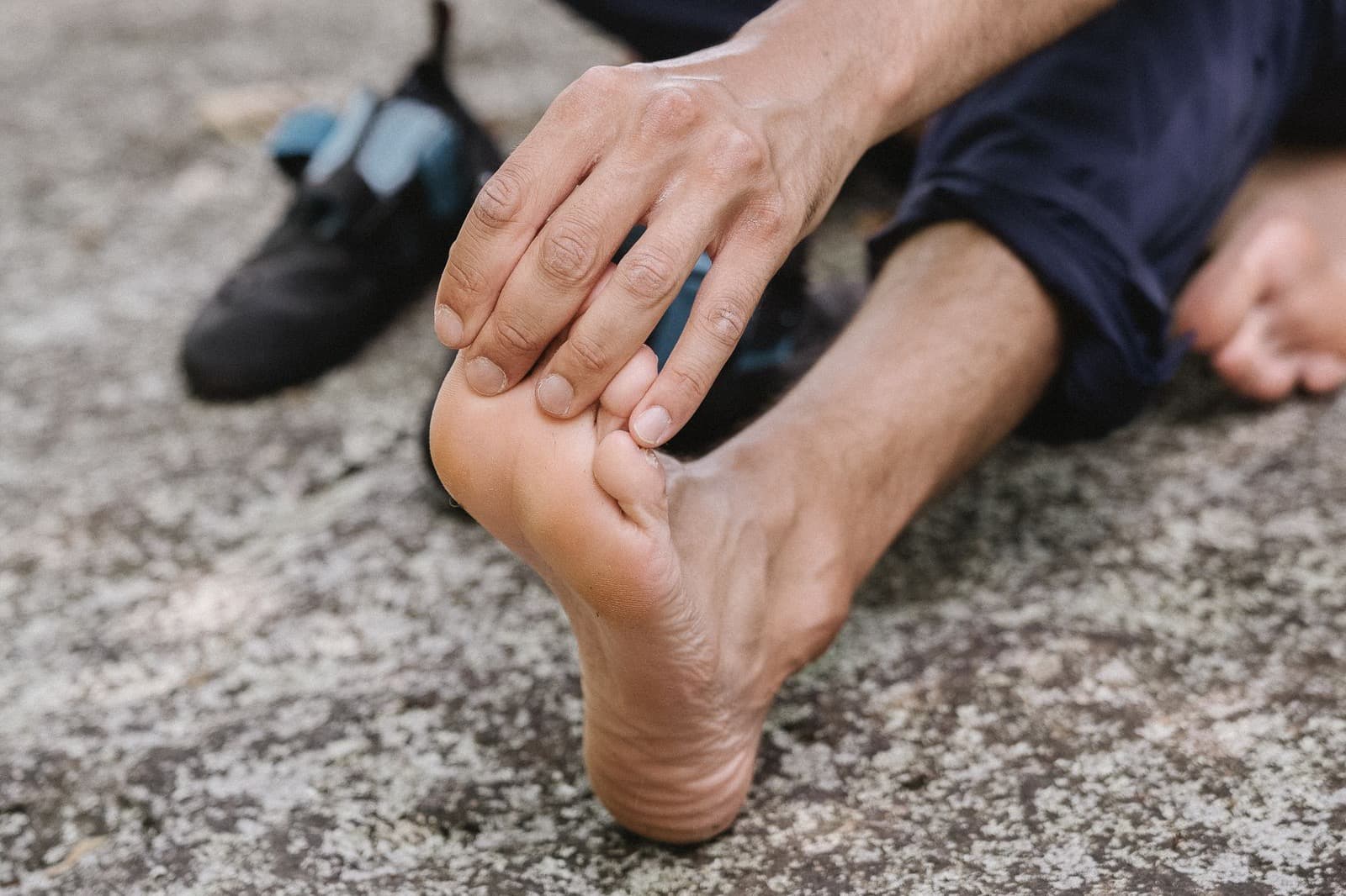 A man sitting on a rock, his hand on the top of his bare foot