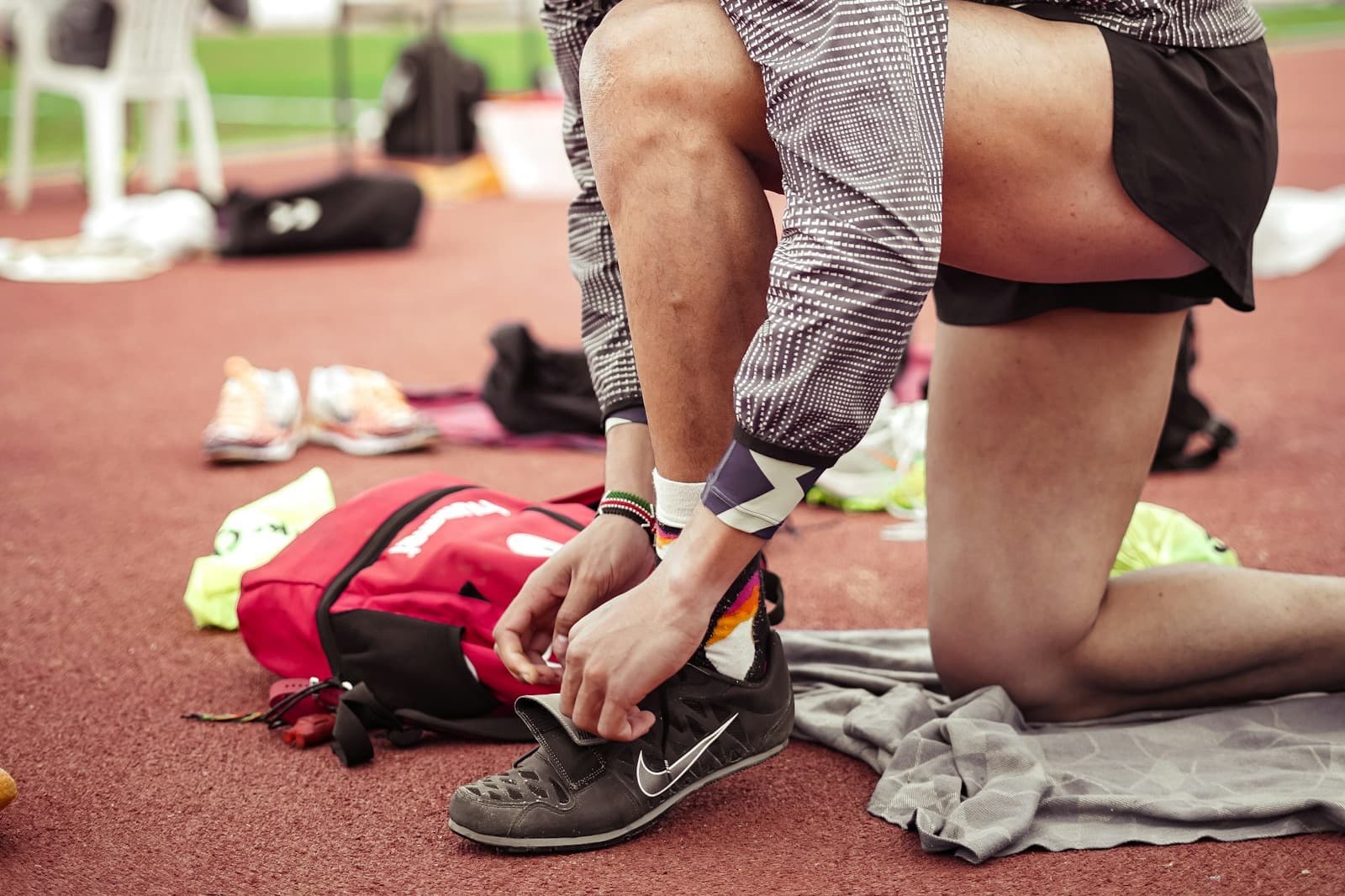 A man crouching to tie his running shoes before a race