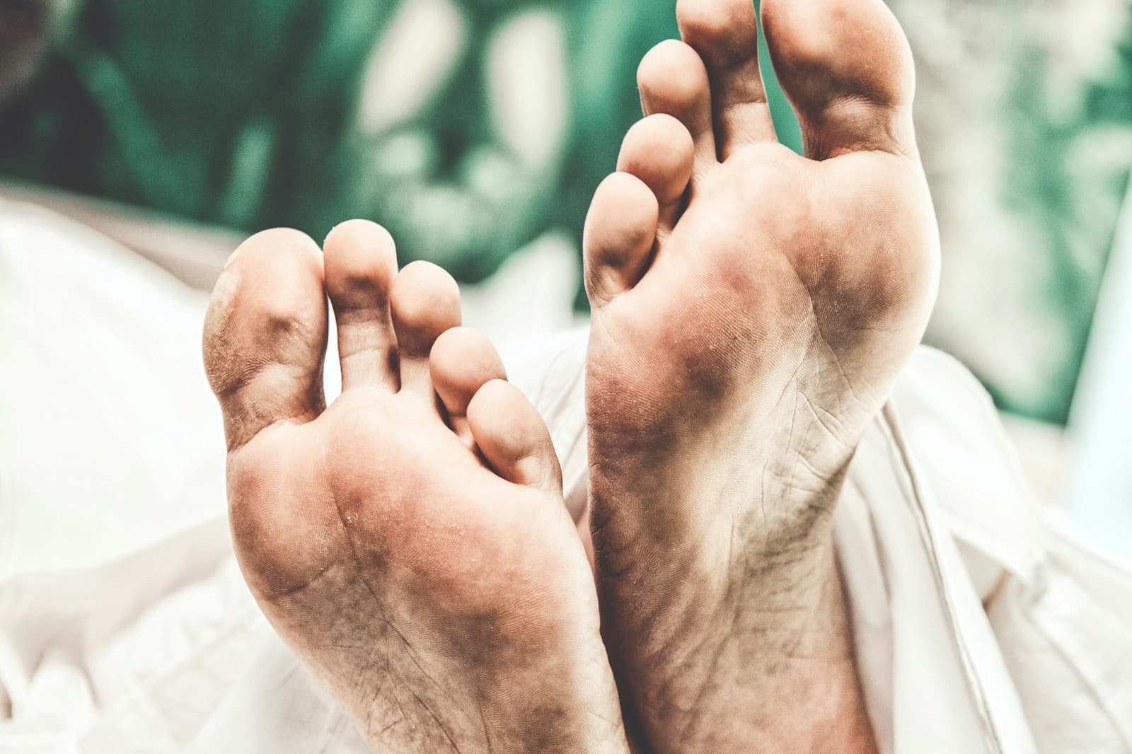 A man's bare soles resting on a bed