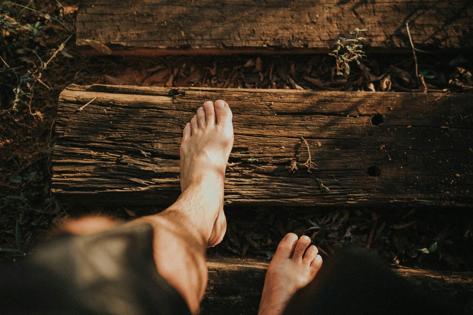 A man's bare feet on a dark wooden plank, seen from above